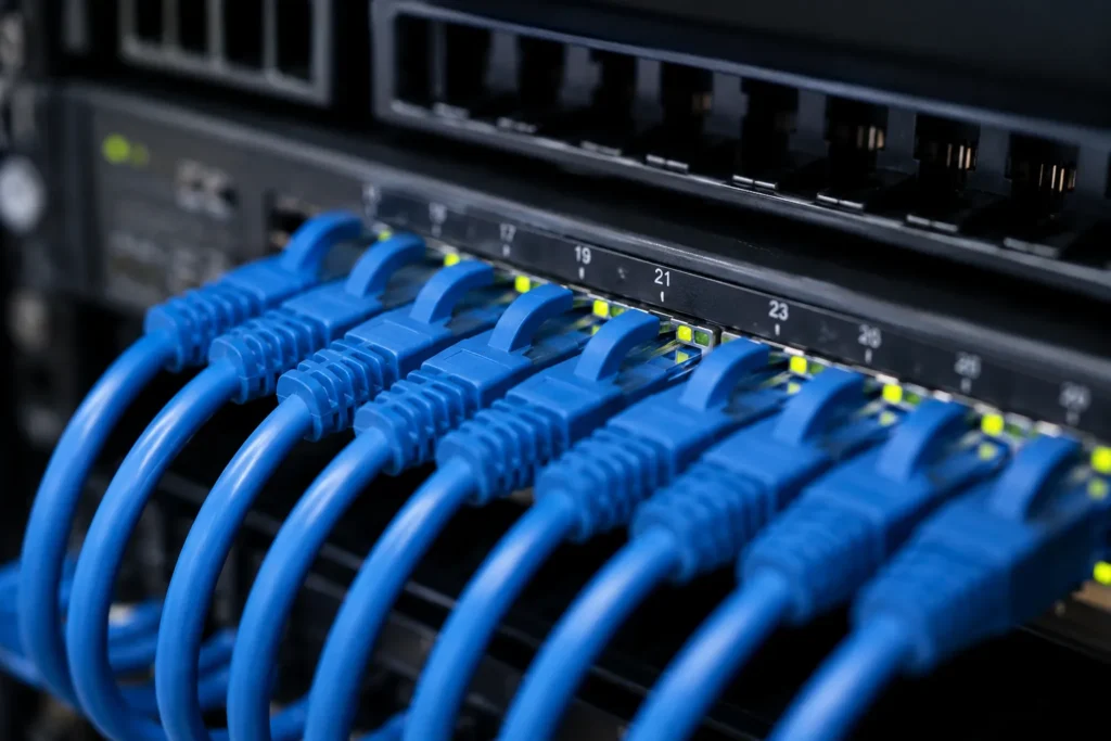 Reti cablate significato: dettaglio di cavi Ethernet collegati a switch di rete per cablaggio strutturato professionale